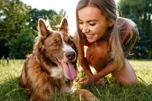 Nahaufnahme eines jungen Weibchens mit ihrem Hund, der im Park auf Gras sitzt